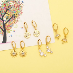 Detail of gold zircon earrings featuring sun, umbrella, and star charms on a yellow base