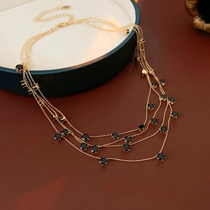 Détail d'un collier multicouche à billes dorées orné d'élégantes pierres noires rondes