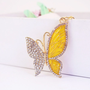 Close-up of golden butterfly keychain with white rhinestones and yellow enamel detail
