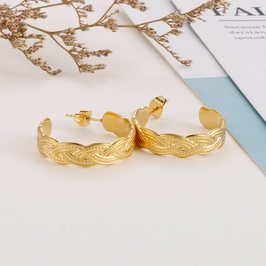 Detail of twisted texture C-shaped hoop earrings in 18k gold plated stainless steel