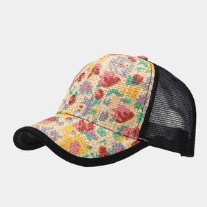Detail view of woven straw front panel with floral print and breathable mesh trucker hat