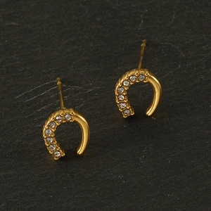 Gros plan de boucles d'oreilles en C dorées 18K avec zircons brillants sur pierre