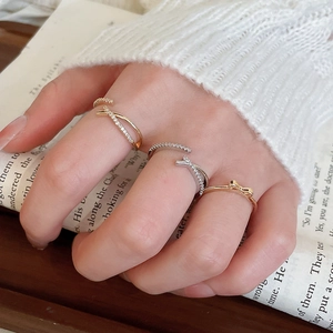 Close-up of minimalist gold bow ring and zircon stackable bands on a hand