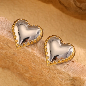 Detail of silver heart earrings with textured gold border on a natural stone surface