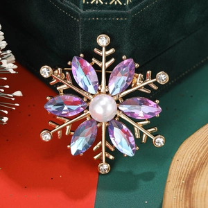 Macro view of gold snowflake brooch with colorful crystals and center faux pearl