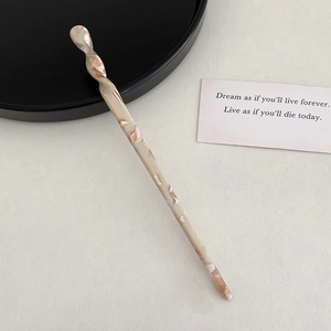 Macro detail of twisted acetate hair pin with elegant beige marble pattern texture
