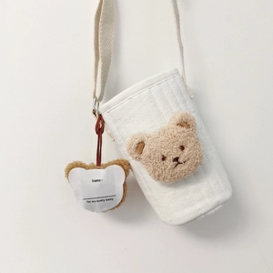 Detail of white quilted fabric water bottle bag with a plush brown bear embroidery
