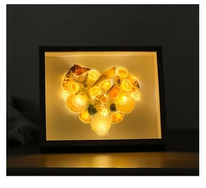 Macro shot of seashell heart mosaic in wooden frame with warm LED lighting effect