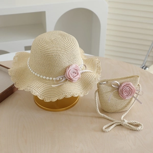 Detail of straw hat with pink fabric roses and matching mini crossbody bag for girls