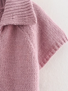 Close-up of the pink knit texture with lapel and shoulder details on the V-neck sweater