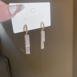 Close-up of golden geometric earrings with sparkling clear cubic zirconia stones