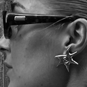 Artistic monochrome close-up of star-shaped stainless steel earrings and sunglasses