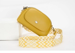 Detail van gele lederen crossbodytas met brede schouderband met geometrisch patroon