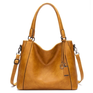 Detailed close-up of mustard yellow tote bag with pebble leather texture and metal tag
