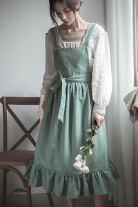 Detail view of green cotton apron featuring vintage ruffles and waist tie on a model
