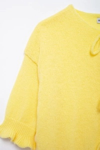 Detailed close-up of yellow knit cardigan showing soft fabric texture and tie-neck collar