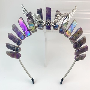 Macro shot of silver metal crown with iridescent crystals, moon and wing details
