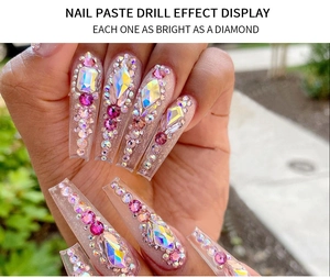 Close-up of long transparent nail tips with colorful rhinestones for diamond-like shine