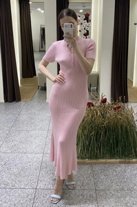 Dettaglio di un abito lungo in maglia a coste rosa con scollo a goccia e laccetto