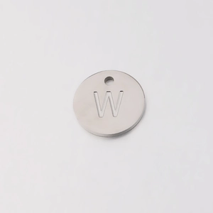 Macro detail of 12mm stainless steel round pendant with engraved capital letter W