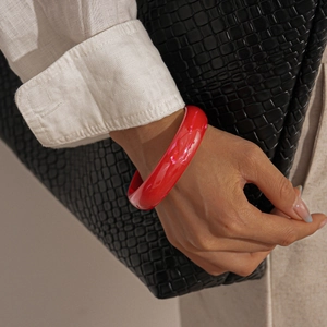 Close-up of a wide glossy red resin bangle with a minimalist round geometric design