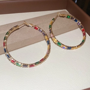 Close-up of rainbow baguette-cut zircons on gold-plated hoop earrings with sharp details