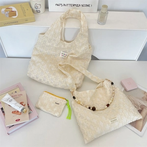 Three-piece set of off-white lace bags featuring intricate floral textures and beaded strap