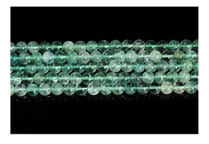 Macro shot of natural green fluorite round beads with translucent texture and icy cracks