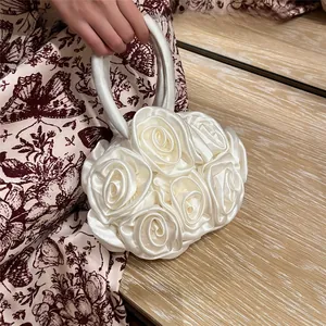 Close-up of white satin rose floral handbag with a round handle and 3D petal texture