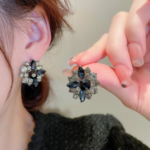 Detailed close-up of a vintage floral earring featuring deep blue rhinestones on model