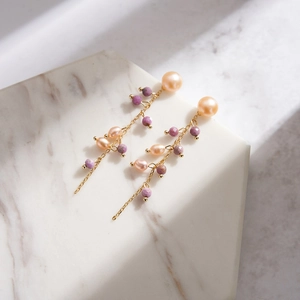 Detail of long drop earrings with pale pink pearls, purple beads and fine gold chain