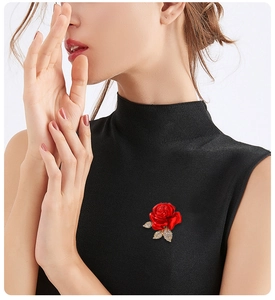 Elegant red rose brooch with gold leaves and crystals worn on a black sweater