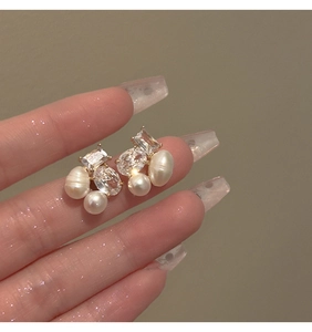 Macro shot of geometric gold earrings featuring cubic zirconia and freshwater pearls