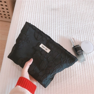 Detail of black cosmetic bag with embossed 3D floral embroidery and Simple Wish label