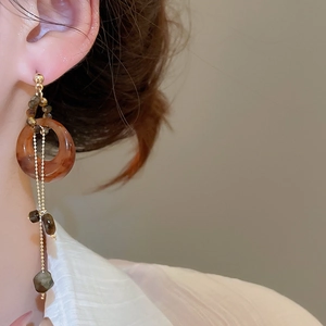 Gros plan de boucles d'oreilles en résine œil de tigre avec chaînes dorées sur mannequin