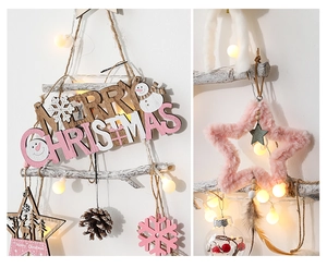 Detail of wooden Merry Christmas sign with pink plush stars and warm LED globe lights