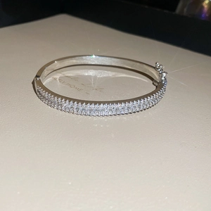Detail of silver bangle featuring double rows of zircons and a secure snap clasp