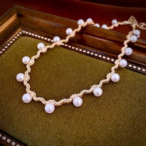 Detail of vintage gold wave pearl choker necklace with white pearls on green velvet