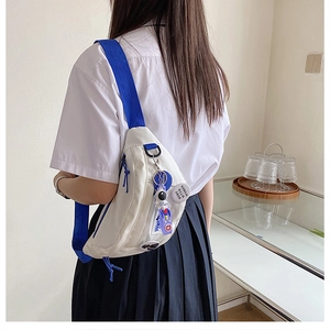 Detail of white nylon chest bag with blue strap and cute astronaut charm accessory