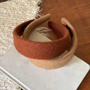 Dettaglio di cerchietti imbottiti in peluche nei colori ruggine e cammello su un tavolo