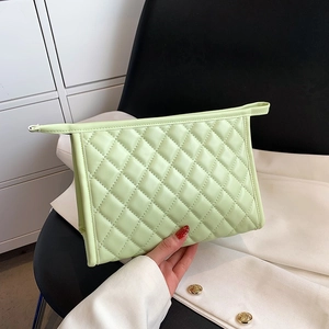 Quilted light green makeup bag in soft faux leather shown by model in natural light