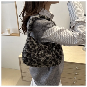 Detailed view of the dark leopard print faux fur shoulder bag worn by a model