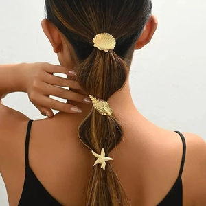 Close-up of golden starfish, seashell, and conch hair clips worn on a model ponytail
