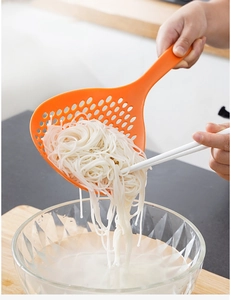 Long handle orange kitchen colander straining noodles from a bowl with chopsticks