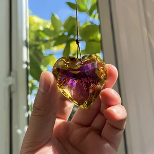 Detail of 45mm heart crystal prism with yellow and purple gradient held against sunlight