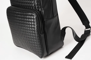 Close-up of black woven leather texture and metal zipper detail on casual business backpack