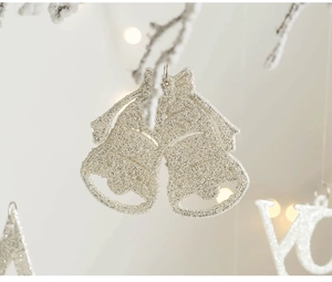 Detail of champagne gold glitter Christmas bells with bow on snow-covered tree branches