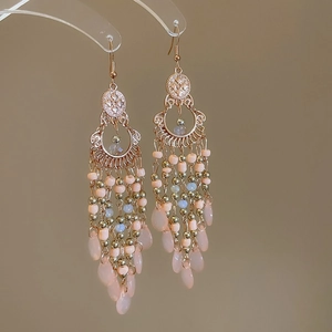 Detail of vintage bohemian beaded drop earrings with golden metal and peach tassels