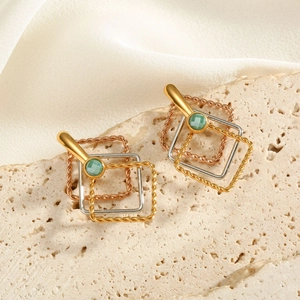 Macro detail of geometric multi-layered square earrings with green gemstone and mixed metal textures