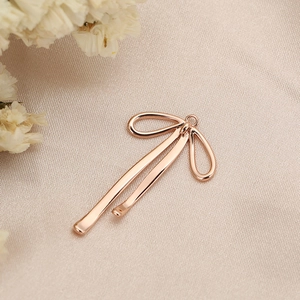 Detailed view of rose gold bow pendant accessory on elegant champagne satin fabric